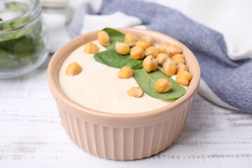 Tasty chickpea soup in bowl on white wooden table, closeup