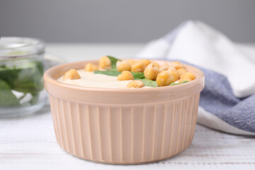 Tasty chickpea soup in bowl on white wooden table, closeup