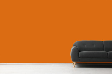 Stylish grey sofa near orange wall indoors, space for text. Interior design