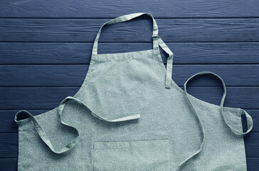 Color apron with pattern on grey wooden table, top view