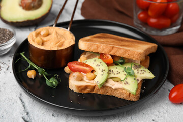 Delicious sandwich with hummus and vegetables on white textured table, closeup