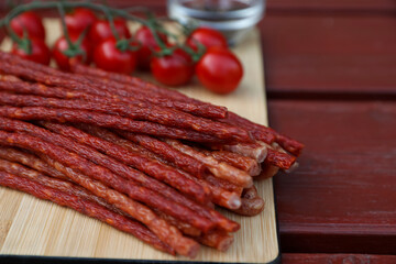 Tasty dry cured sausages (kabanosy) on wooden table, closeup