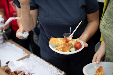 Food in plate in your hand. Man eating on street. Delicious food.