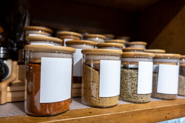 Selective focus on blank labeled seasoning jars inside a cupboard in a home kitchen