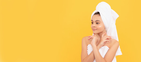 Girl with healthy skin, facial treatment, smiling teen girl in shower towel with cream on face. Cosmetics and skin care for teenager child, poster design. Beauty kid girl banner with copy space.