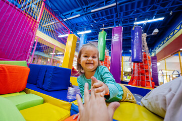 Baby girl playing at indoor play center playground.  Give high five to father.