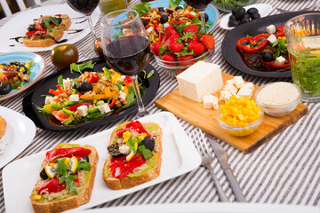 Fototapeta na wymiar Delicious variety of vegetarian products and dishes with wine on striped fabric background .
