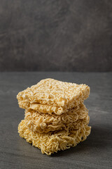 Square dry egg noodles in a briquette on a gray stone marble (slate) background.