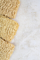 Square dry egg noodles in a briquette on a light beige stone marble background