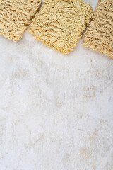 Square dry egg noodles in a briquette on a light beige stone marble background