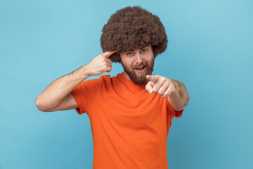 Hey, you are kidding. Man with Afro hairstyle surprised face holding finger near head and pointing...