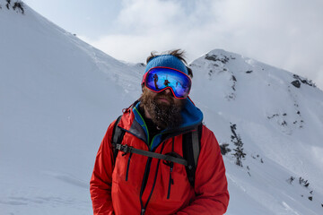 Fototapeta na wymiar A mountain guide with a beard and in a mask among the mountains and slopes