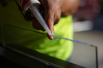 The craftsman's hand uses a silicone adhesive to connect the glass to the glass to stick together.