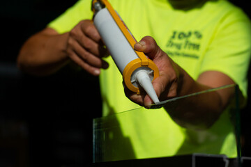 The craftsman's hand uses a silicone adhesive to connect the glass to the glass to stick together.