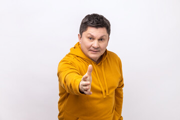 Portrait of middle aged man standing with outstretched hand, offering handshake to partner, greeting on job interview, wearing urban style hoodie. Indoor studio shot isolated on white background.