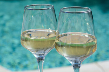 Glasses of tasty wine near swimming pool, closeup