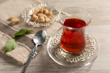 Glass of traditional Turkish tea on white wooden table, closeup. Space for text