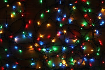 Colorful Christmas lights on wooden table, top view