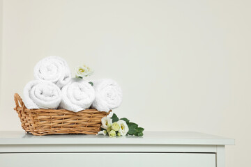 Soft folded towels and flowers on white table, space for text
