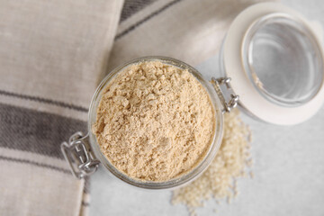 Sesame flour in glass jar on grey table, top view