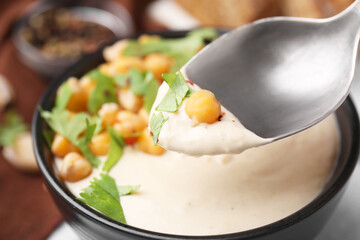 Eating tasty chickpea soup on table, closeup