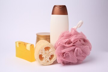 Pink shower puff, loofah sponge and cosmetic products on white background
