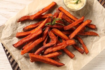 Board with delicious sweet potato fries and sauce on white wooden table, closeup