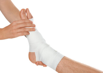 Doctor examining patient's foot wrapped in medical bandage on white background, closeup