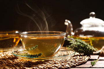 Cup of aromatic herbal tea and thyme on wooden table