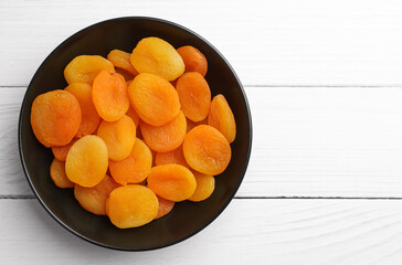 Plate of tasty apricots and space for text on white wooden table, top view. Dried fruits