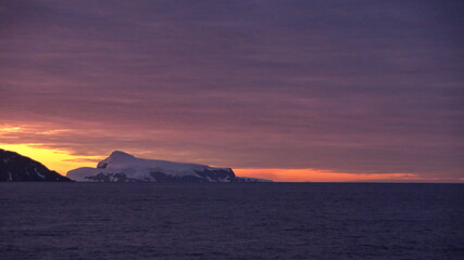 Naklejka na ściany i meble Sunset over the silhouette of mountains at Cierva Cove, Antarctica