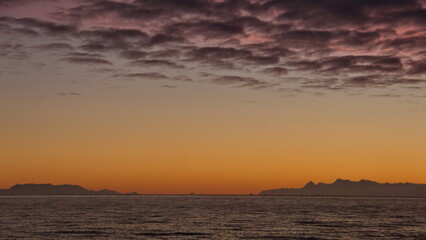 Popcorn clouds illuminated pink over the silhouette of a mountain, at sunset at Cierva Cove,...