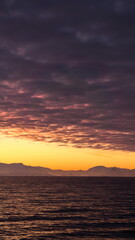 Fototapeta premium Popcorn clouds illuminated pink over the silhouette of a mountain, at sunset at Cierva Cove, Antarctica
