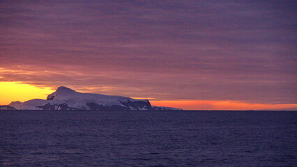 Naklejka na ściany i meble Sunset over the silhouette of mountains at Cierva Cove, Antarctica