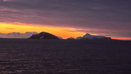 Fototapeta na wymiar Sunset over the silhouette of mountains at Cierva Cove, Antarctica