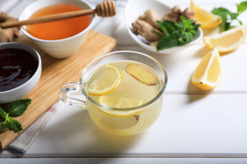 Delicious ginger tea and ingredients on white wooden table