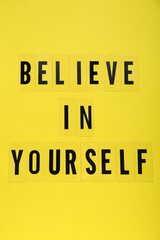 Phrase Believe In Yourself and hearts on yellow background, top view. Motivational quote
