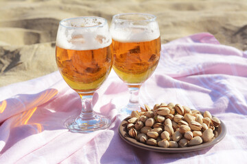 Glasses of cold beer and pistachios on sandy beach