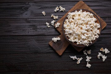 Tasty popcorn on black wooden table, flat lay. Space for text