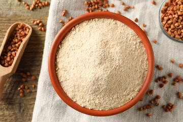 Bowl of buckwheat flour, scoop cloth on wooden table, flat lay