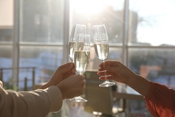 People clinking glasses of champagne in office, closeup. Holiday cheer and drink