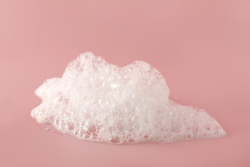 Obraz na płótnie Canvas Fluffy bath foam on pink background, closeup. Care product
