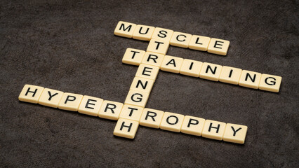 muscle, training for strength and hypertrophy crossword in ivory letter tiles against textured bark...