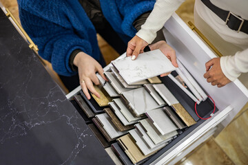Closeup hands creative female interior designer and customer choosing marble stone color
