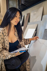 Portrait Asian woman interior designer choosing ceramic tiles or porcelain stoneware at showroom