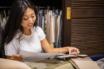 Japanese woman interior designer choosing fabrics sample for curtains, home textile, indoor decor