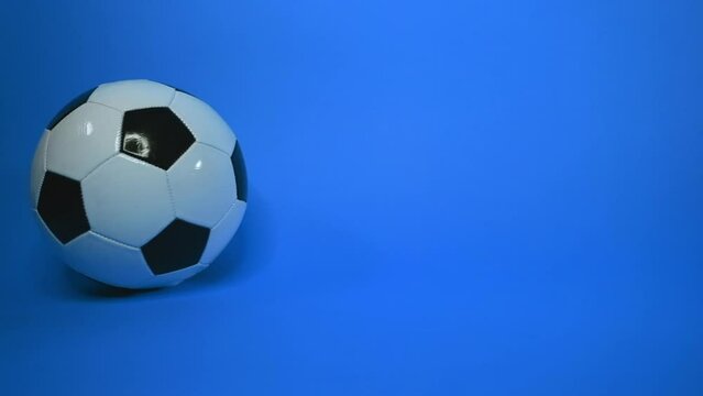 isolated soccer ball is spinning on blue background. leather black and white soccer ball. Sports competition. Football tournament. Place for text, copy space. No people