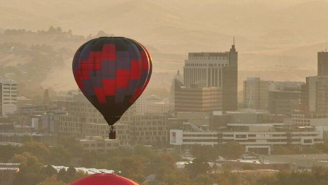 Long shot of a hot air balloon floating above a cityscape.