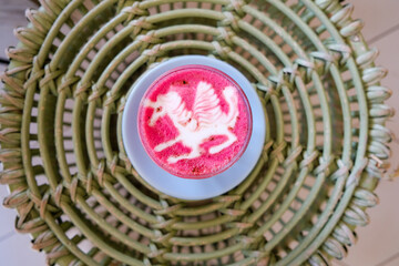 Healthy trendy beetroot latte with latte art in ceramic cup on wooden table. Top view.