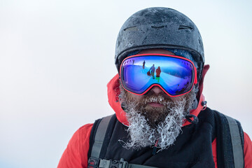 bearded skier in a frozen helmet and mask fending off a team of freeriders